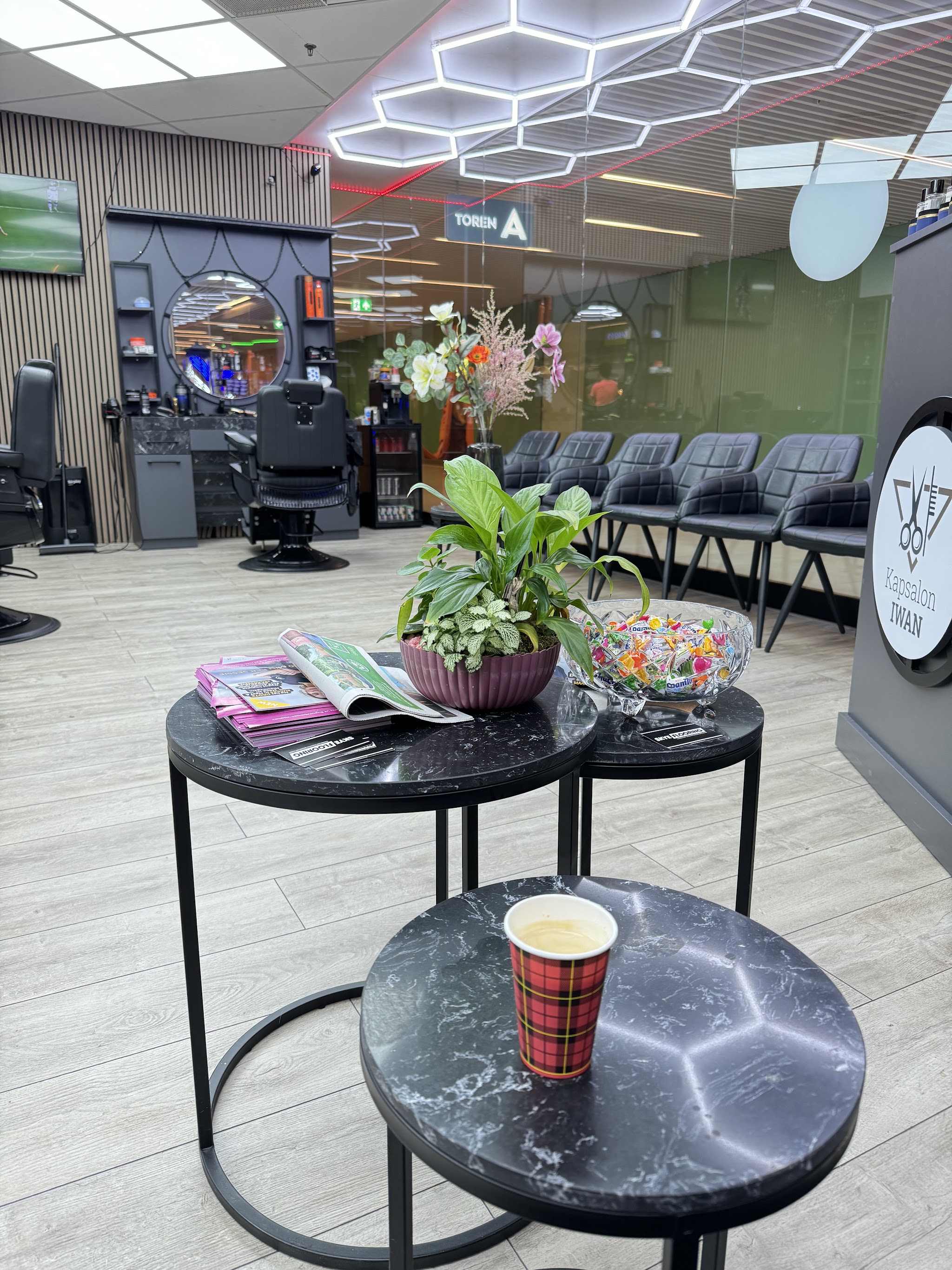De wachthoek met ronde marmeren tafeltjes, een kop koffie, een schaal snoep en zwarte stoelen