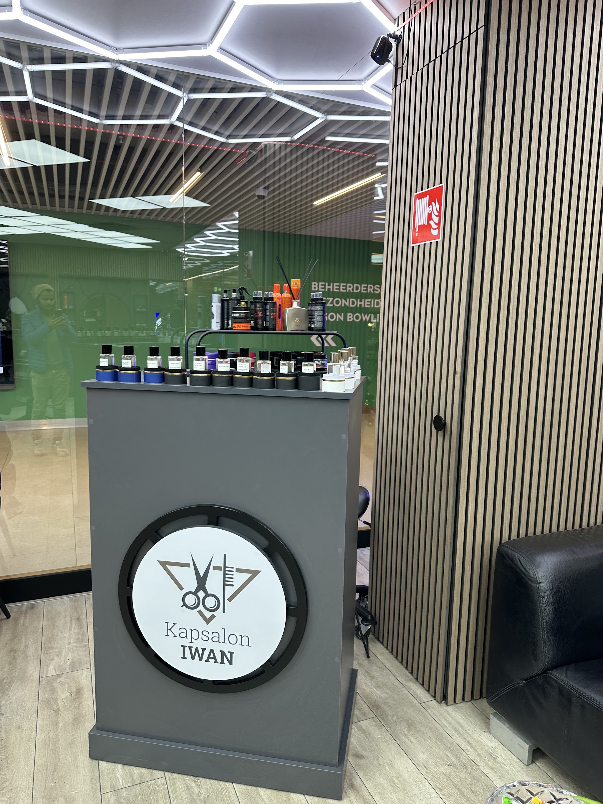 De balie met het ronde logo van Kapsalon IWAN en de producten erboven